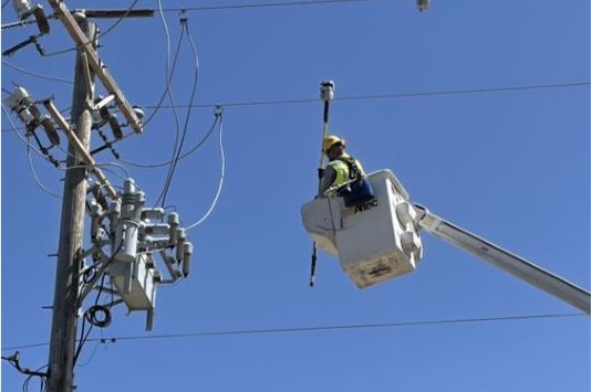 Worker in a cherry picker servicing a power line.