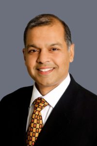 sentient-energy-Venkat Bahl Headshot of Venkat Bahl wearing a suit and smiling.