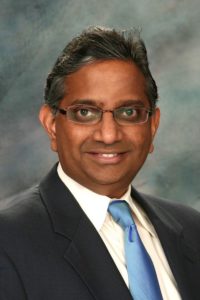 sentient-energy-Giri Iyer Headshot of Giri Iyer wearing a suit and smiling.